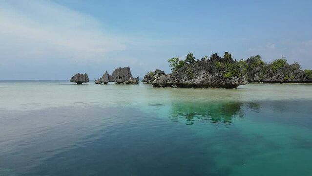 aerial shoot, flight over colourful lagoon with Turquoise water, sand beach and palm trees in Raja Ampat Indonesia