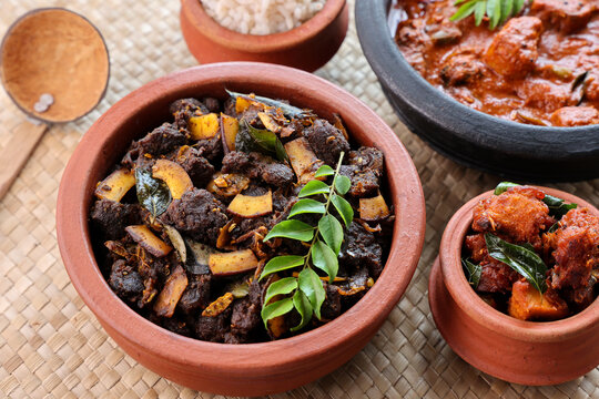 Spicy red beef fry curry and brown rice South Indian dish Kerala, India. side of Ghee rice, Appam, Parotta, Puttu. traditional Christian Muslim feast dish. Buffalo roast, meat pepper fry with coconut.