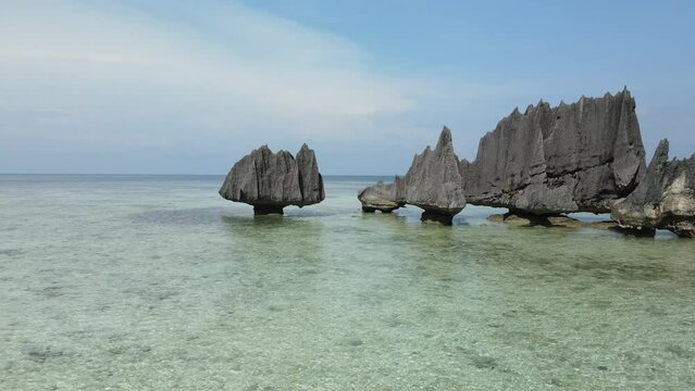 aerial shoot, flight over colourful lagoon with Turquoise water, sand beach and palm trees in Raja Ampat Indonesia