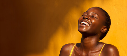 Woman laughs against a yellow wall, her radiant smile complementing her vibrant, tanned skin. - obrazy, fototapety, plakaty