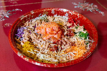 Serving of yusheng or yee sang with raw salmon during Chinese New Year believed to bring good luck and prosperity