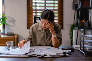 Casual business women stressed and headache while reading and checking financial paper in office