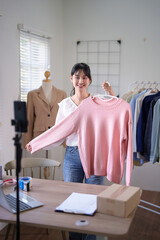 Young asian merchant women using smartphone to recording live streaming and selling clothes online...