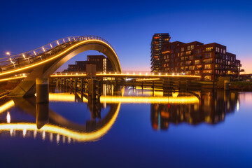 A bridge in the city at night. City lights. The Galaxy Bridge, Purmerend, Netherlands. The bridge on the blue sky background during the blue hour. Architecture and design.