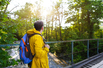 Tourist man walking across wooden bridge