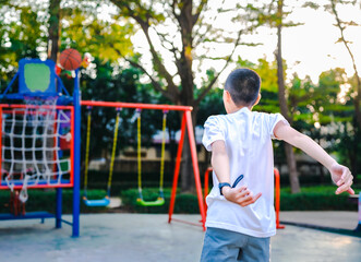 Obraz premium Rear view of a child playing basketball.The child throws the ball into the basket