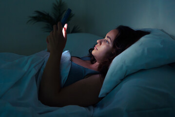 Struggling with sleeplessness and the online world: A youth, ensnared in her bed's embrace, gazes...