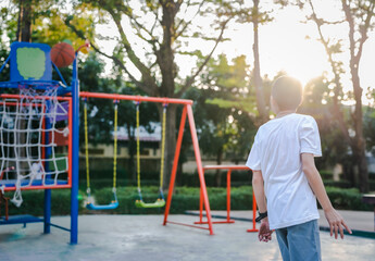 Obraz premium Rear view of a child playing basketball.The child throws the ball into the basket