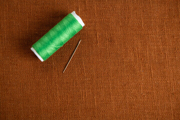 Brown fabric background with thread and needle - 709123424
