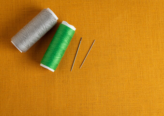 Yellow fabric with spools of thread and needles, textile background, sewing industry - 709123460