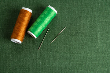 Green textile background with spools of thread and needles - 709123479