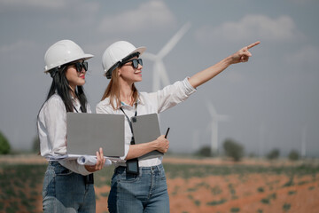 engineer team. renewable energy, power and wind turbine. Electrician or technician man and woman in nature for electricity, eco and green environment engineer working in wind turbine farm at sunset.