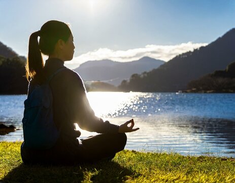 A woman meditating by a lakeside in the morning