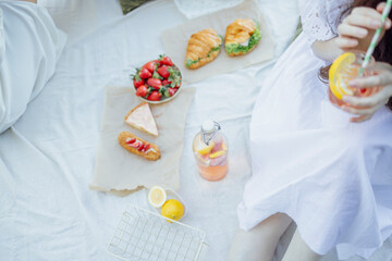 lanket with pillows and food on a wooden bridge. Bottle of strawberry and lemon smoothie
