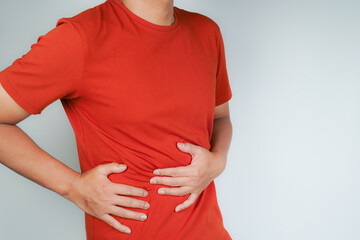 male having stomach ache, bending over and holding hands on stomach, uncomfortable due to stomach...