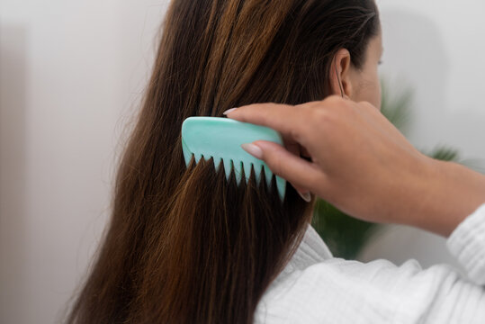 Locks of Love: In a closeup shot, she combs her long, healthy hair in front of a mirror, dedicating time to home hair care. 