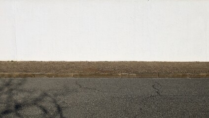 High white plaster wall with porphyry sidewalk and street in front. Background for copy space.	