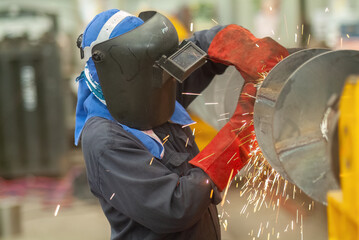 Worker using an angle grinder, making a screw conveyor
