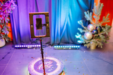 close-up of a 360-degree photo booth spinner with a mounted smartphone, set against a colorful...