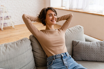 pretty young woman realxing at home sitting on sofa, smiling, happy, free time