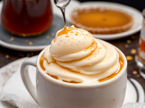 close up of a cup full of vanilla ice cream and syrup dripping on top of it.