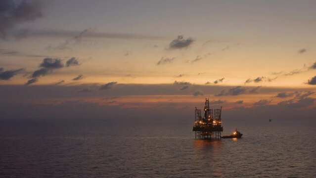 Aerial view of silhouette offshore jack up drilling rig during sunset - oil and gas industry