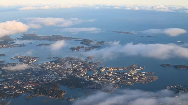View from the window of an airplane. Flight by the coastal city and the sea, flying at cloud level