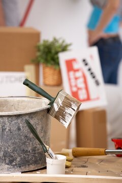 Young couple painting their new house with paint roller, equipment in focus.