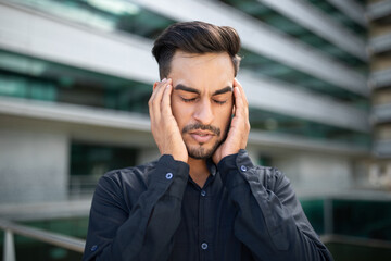 Obraz premium Portrait of stressed middle eastern businessman suffering from headache outside