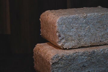 Close-up of a wood briquettes, pressed sawdust on a dark background. Solid fuel from wood chips and flax. Nature-friendly ecological fuel from renewable resources