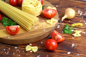 There are pasta and vegetables on a wooden table.