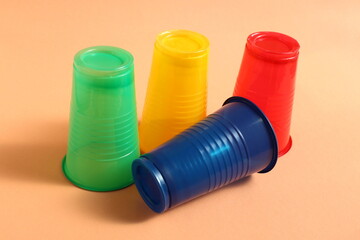 Several multi-colored plastic cups stand on an orange background.