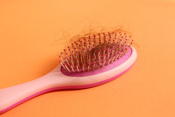A pink curl with a tuft of hair lies on an orange background.