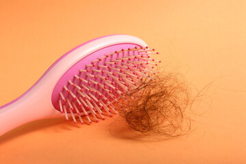 A pink curl with a tuft of hair lies on an orange background.