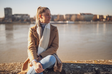 Sad woman sitting by the river. Toned image.	