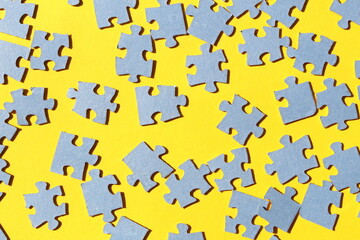 Blue small scattered puzzles lie on a yellow background.	