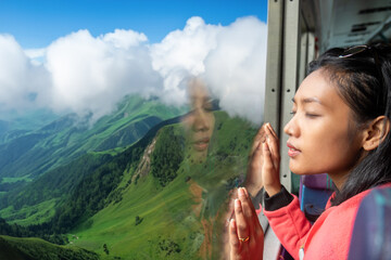 A young woman is looking dreamily into the valley from a moving bus