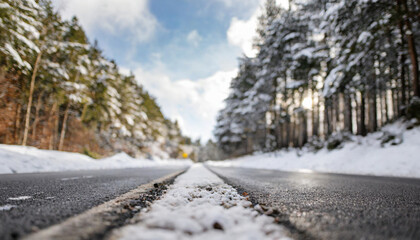 Snow-covered winter landscape with winding asphalt road through serene forest, capturing the tranquil beauty of a cold season journey
