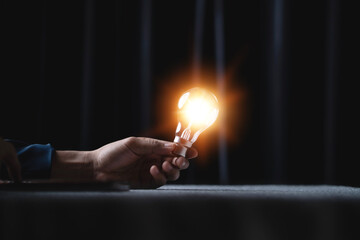 Creative idea with a glowing light bulb. Inspiration. Sustainable business development. Human hand...