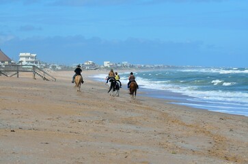 People horseback riding at the ocean beach