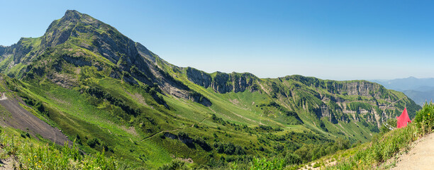 Fototapeta na wymiar View of the Caucasus Mountains from Polyana peak in Sochi, Russia on a sunny summer day - panorama