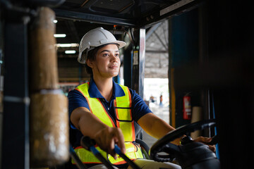 female factory worker. female forklift operator working in a warehouse. Portrait of young Indian woman driver sitting in forklift and smiling working in warehouse. - obrazy, fototapety, plakaty