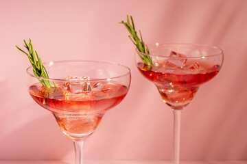 Refreshing cocktail with rosemary in a glass on a bright background. Summer party concept.