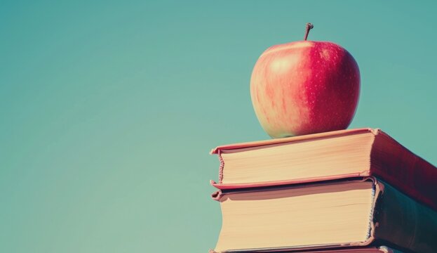 an apple on top of a stack of books with blue sky