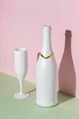 White champagne bottle and champagne glass on bright background.. Minimal party concept.
