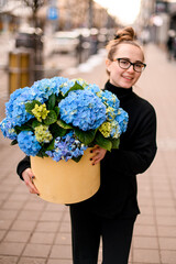 Fototapeta premium Hat box with beautiful luxury bouquet of blue hydrangeas in woman florist hands.