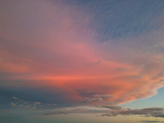 an evening sky with pink and blue clouds over the sea