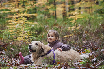 Charming child and dog walking in the forest in Denmark