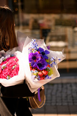 Woman florist walks on the street with two delicate bouquets of different flowers as gift