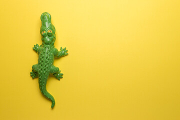 Green crocodile toy on bright yellow background. Minimal art concept.